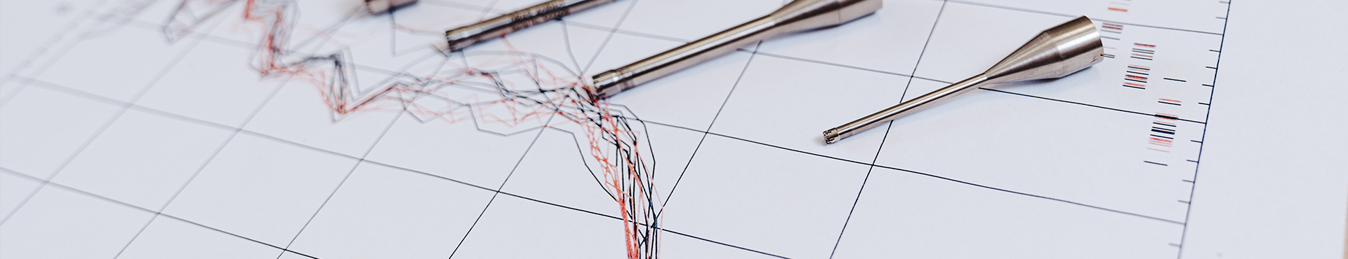 Mehrere akustische Messsonden liegen auf einem Diagramm mit aufgezeichneten Schallmesskurven.